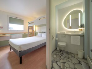 A hotel room with a bed, a bathroom with a sink and toilet, and a window with a Renault sign. - ibis budget Sarrebourg Buhl (Buhl-Lorraine)