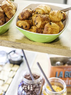 A bowl of croissants on a wooden surface.