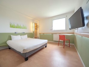 A hotel room with a bed, a chair, a TV, and a window. - ibis budget Sarrebourg Buhl (Buhl-Lorraine)