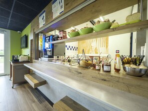 A buffet setup with various food items and condiments on display. - ibis budget Sarrebourg Buhl (Buhl-Lorraine)