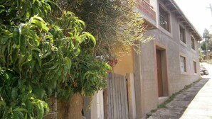 A residential building with a yellow exterior, a wooden fence, and a paved pathway leading to the entrance. - Samay Wasi Salakancha (Isla Amantani)
