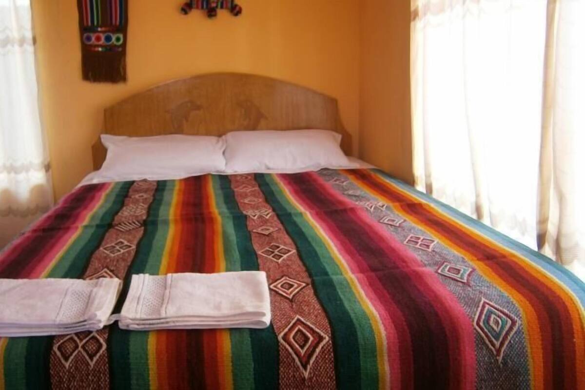 A bed with a colorful striped bedspread and two neatly folded towels.