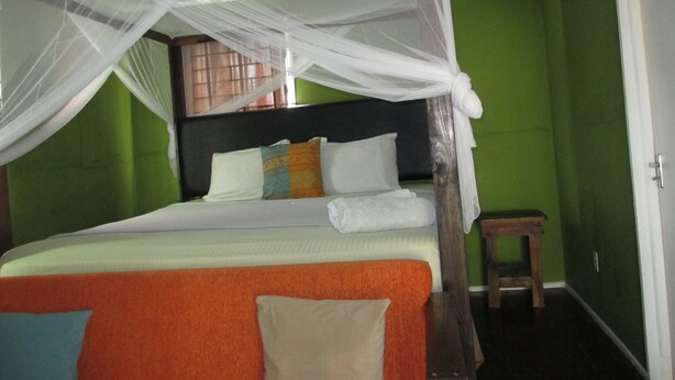 A bed with a canopy, a bedside table, and a green wall.