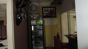A room with a refrigerator stocked with beverages, a clock on the wall, and a poster.