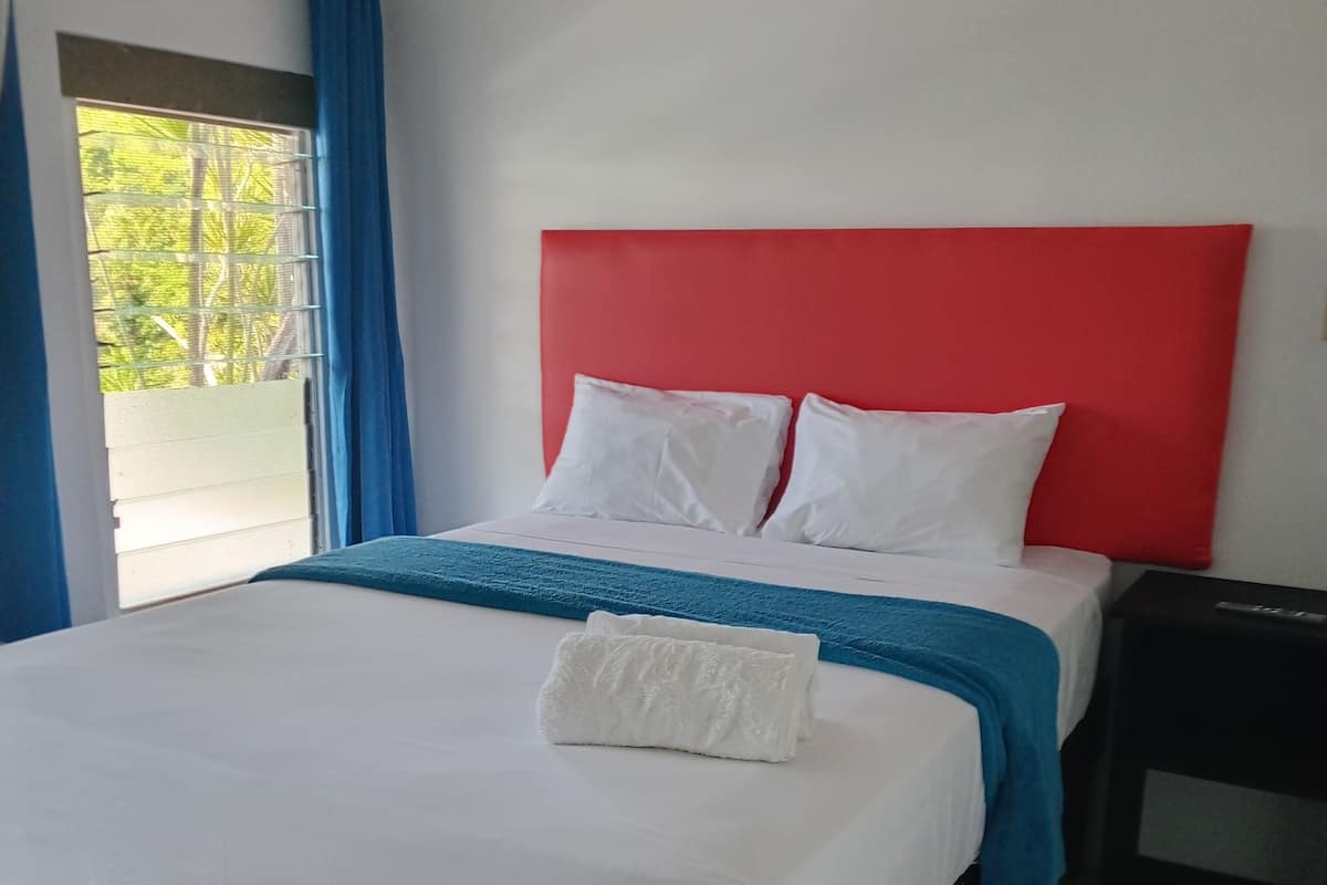 A hotel room with a bed, a nightstand, and a window with curtains.
