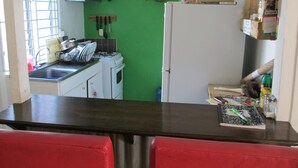A kitchen with a green wall, white cabinets, a stove, and a refrigerator.
