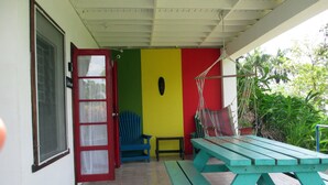 A covered patio with a picnic table and chairs, a door, and a wall with a colorful vertical stripe pattern.