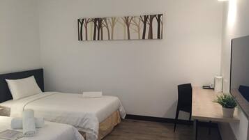 A hotel room with two beds, a desk, a chair, a TV, and a wall art piece.