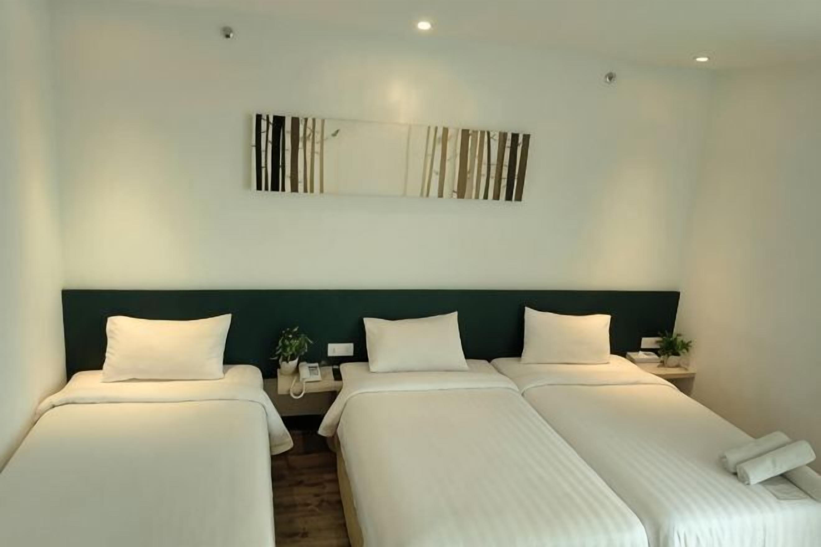 A hotel room with two beds, a nightstand, a mirror, and a wall-mounted artwork.
