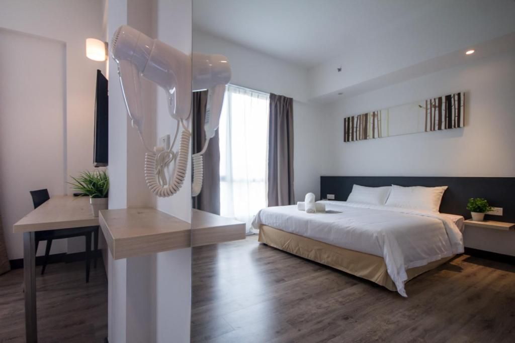 Een hotelkamer met een bed, nachtkastje en een bureau met een stoel.