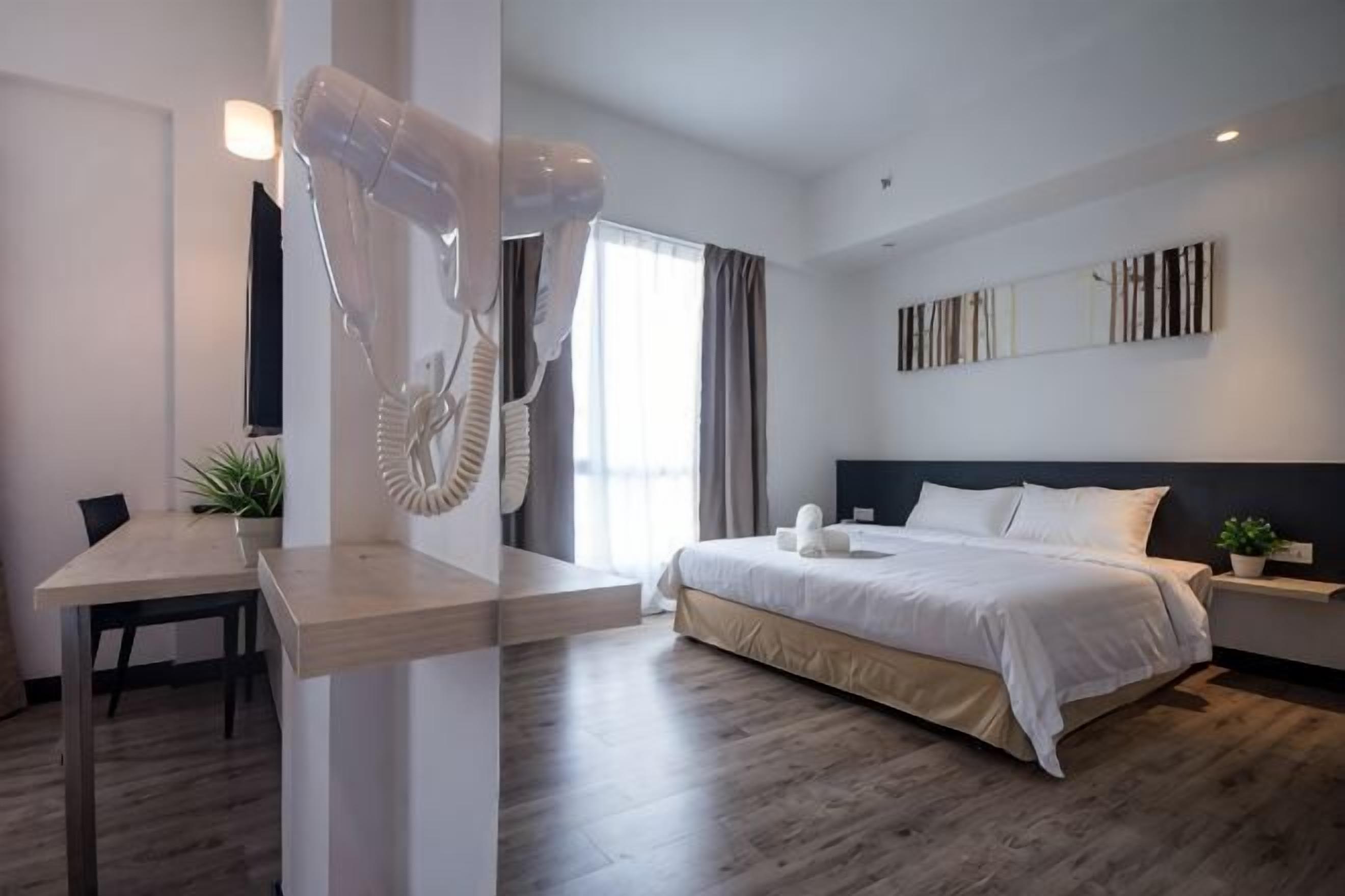 A hotel room with a bed, bedside table, and a hairdryer.