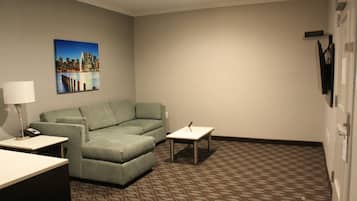 Une chambre d’hôtel avec un tapis à motifs, un canapé vert, une petite table et une lampe.