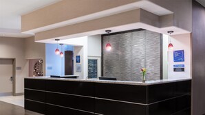 A modern reception desk with a black finish, a glass partition, and pendant lighting.