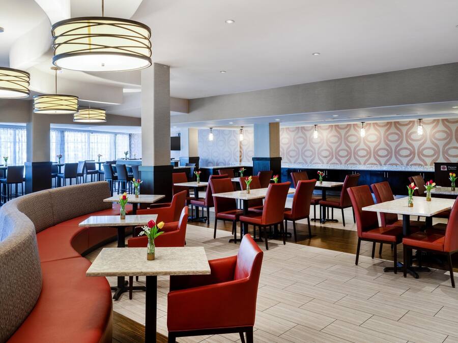 A modern hotel lobby with a mix of seating options, including a curved red sofa and individual tables.