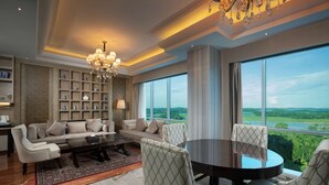 A modern living room with a sofa, chairs, a coffee table, and a chandelier. There is a large window with a view of greenery. - Wyndham Panbil Batam (Batam)
