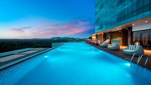 A rooftop infinity pool with a view of the cityscape and mountains at dusk. - Wyndham Panbil Batam (Batam)