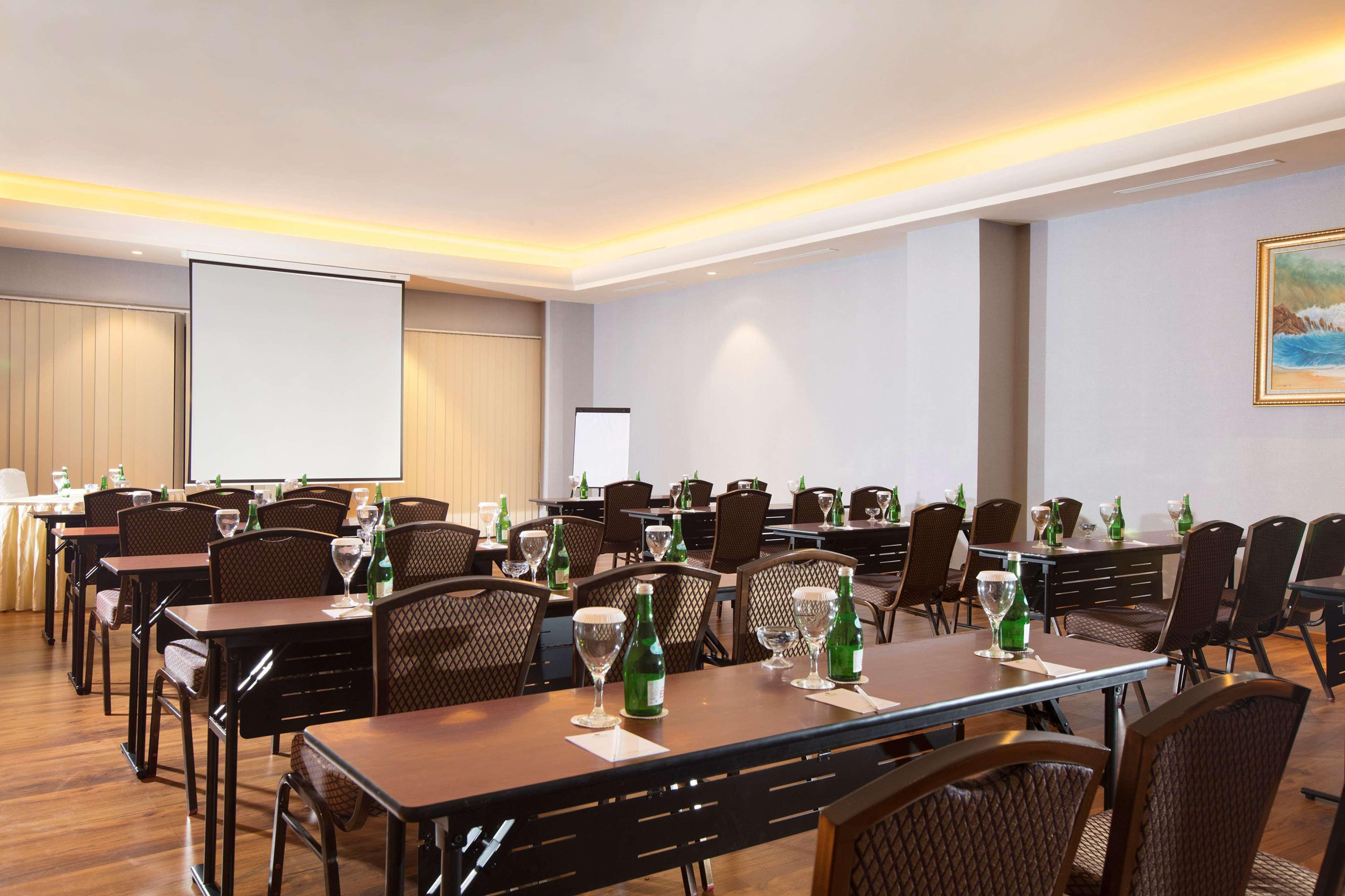 A conference room with multiple tables, chairs, and a projector screen.
