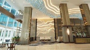 A modern lobby with a glass reception desk, seating area, and a patterned carpet. - Wyndham Panbil Batam (Batam)