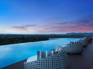 A poolside area with lounge chairs and a view of a natural landscape. - Wyndham Panbil Batam (Batam)