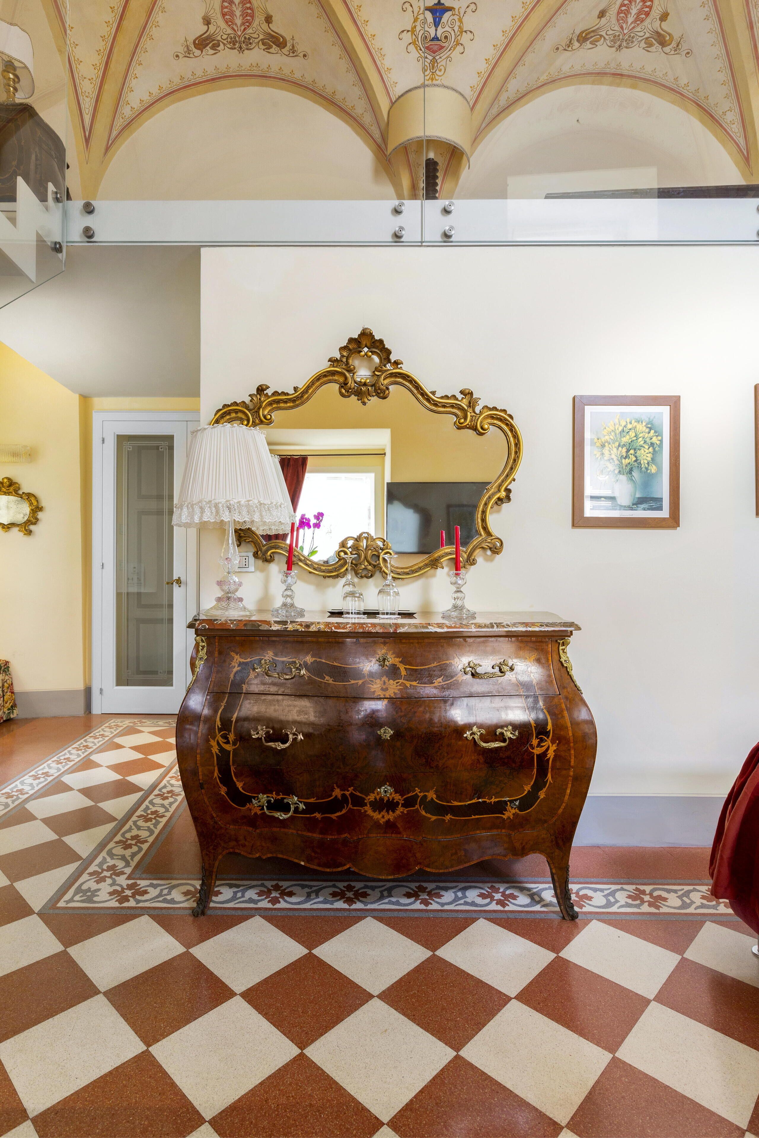 A checkered floor, ornate mirror, and a wooden dresser with drawers.