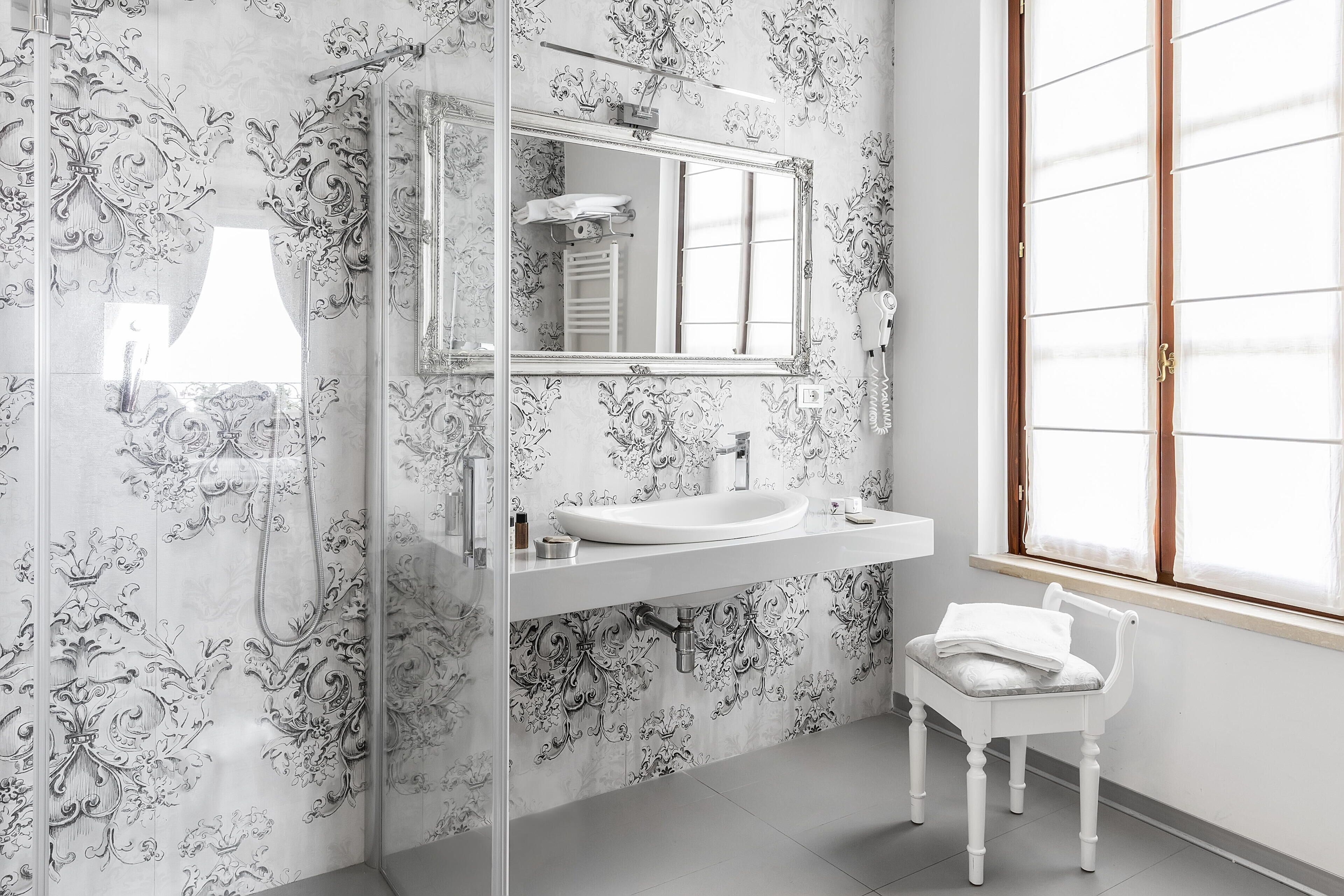 Un baño con un espejo grande, un lavabo y una silla.