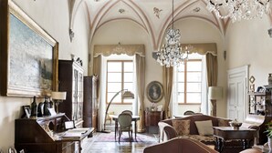 A spacious room with a large chandelier, a piano, and a dining area with a table and chairs. - Residenza d'Epoca Palazzo Borghesi (Siena)