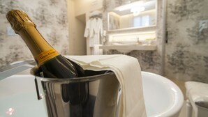 A bathroom with a champagne bottle in a glass container, a white sink, and a mirror above the sink. - Residenza d'Epoca Palazzo Borghesi (Siena)