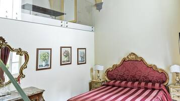 Ein Schlafzimmer mit kariertem Boden, einem Bett mit gestreifter Bettdecke, einem Spiegel und gerahmten Bildern an der Wand.