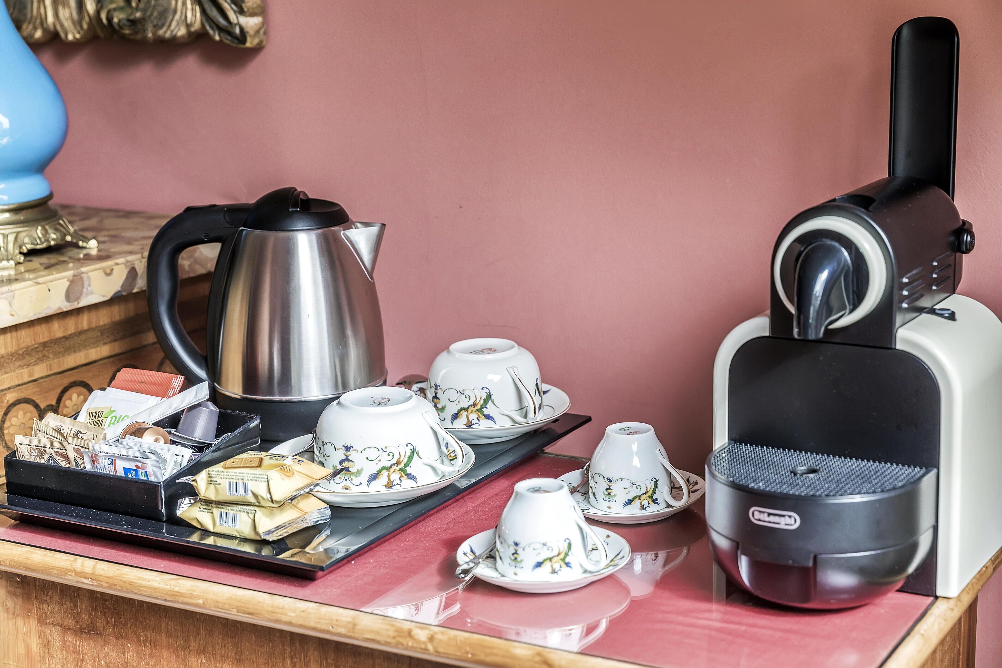 Uma bancada de cozinha com cafeteira, bule, xícaras e uma bandeja com saquinhos de chá.