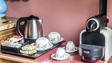 Uma bancada de cozinha com cafeteira, bule, xícaras e uma bandeja com saquinhos de chá.
