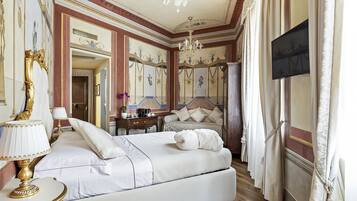 Ein luxuriöses Schlafzimmer mit einem großen Bett, einem Schreibtisch und einem Fernseher.