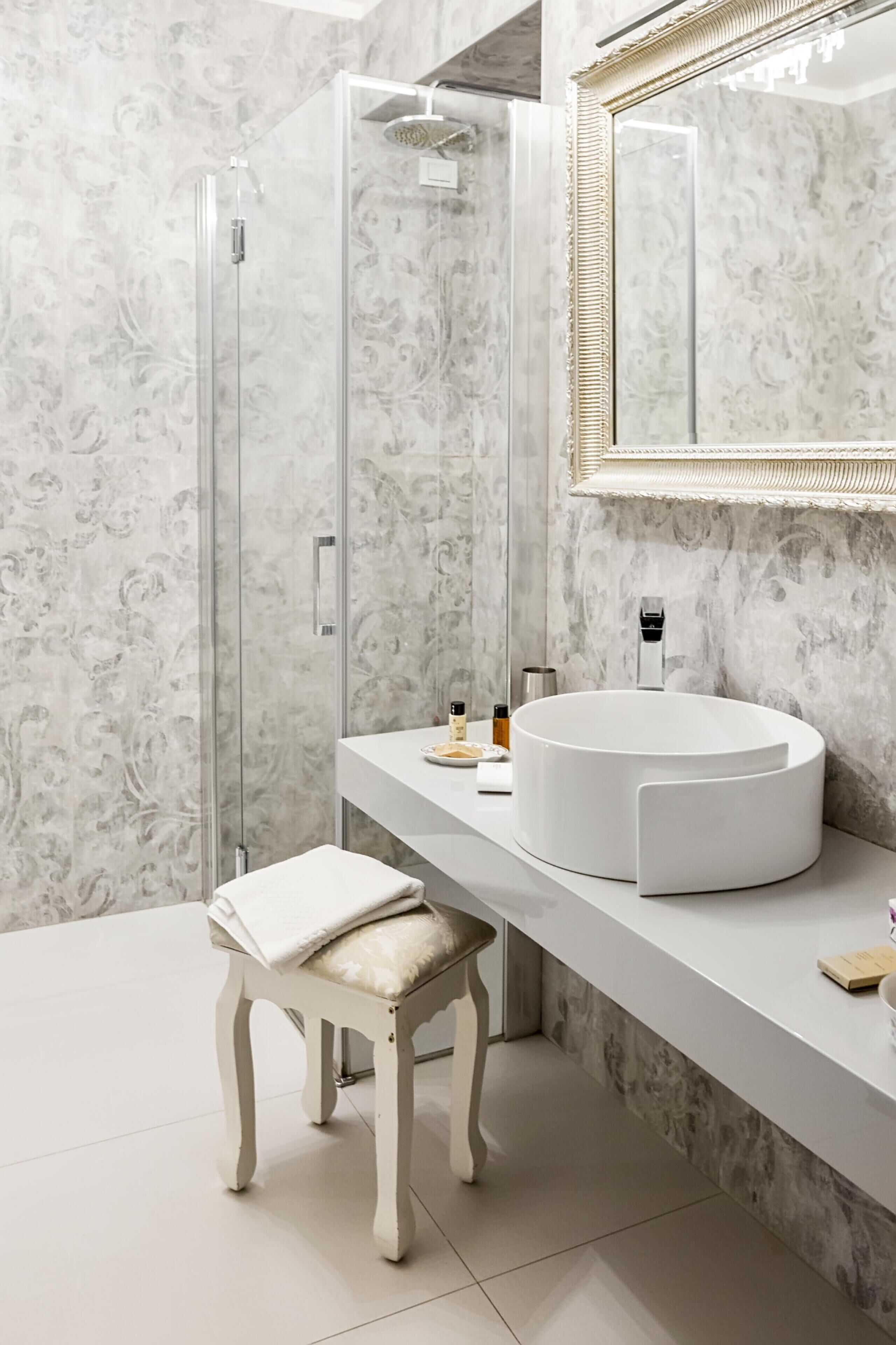 A modern bathroom with a glass-enclosed shower, a round sink, and a vanity with a mirror.