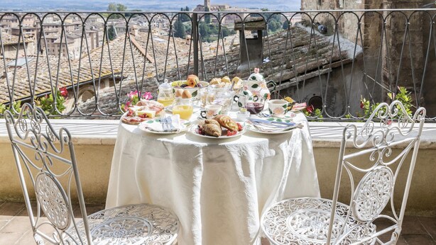 A table set with breakfast items on a balcony overlooking a historic town. - Residenza d'Epoca Palazzo Borghesi (Siena)