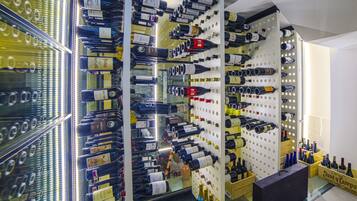 A wine cellar with shelves of bottles, a wine rack, and a counter with more bottles.