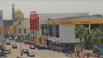 Vista de la calle con varios edificios, incluyendo un banco con el rótulo Maybank y una mezquita con una cúpula dorada.