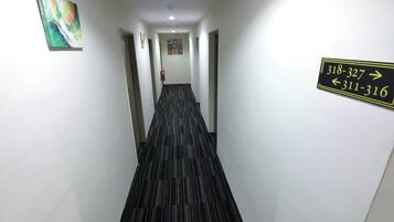 Et hotelkøkken med skilte der viser vej, en brandslukker og et farverigt abstrakt maleri på væggen.