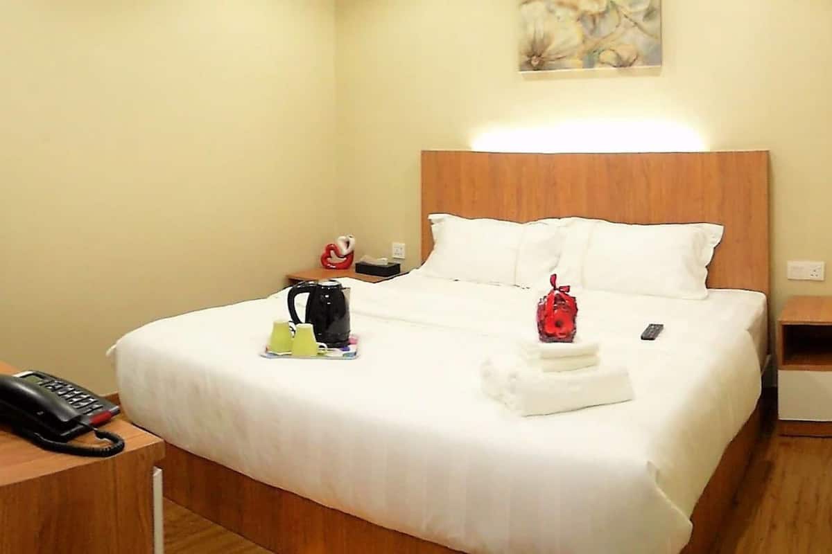 A hotel room with a bed, bedside table, and a nightstand.