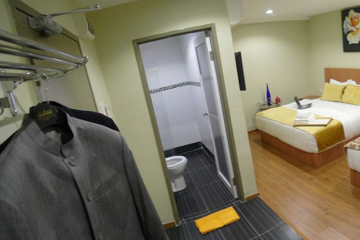 A hotel room with two beds, a bathroom, and a mirror.