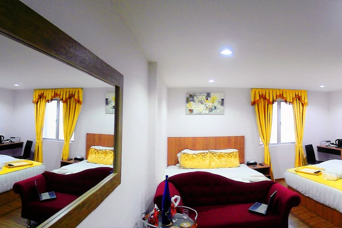 A hotel room with two beds, a mirror, a desk, a chair, and a bathroom.