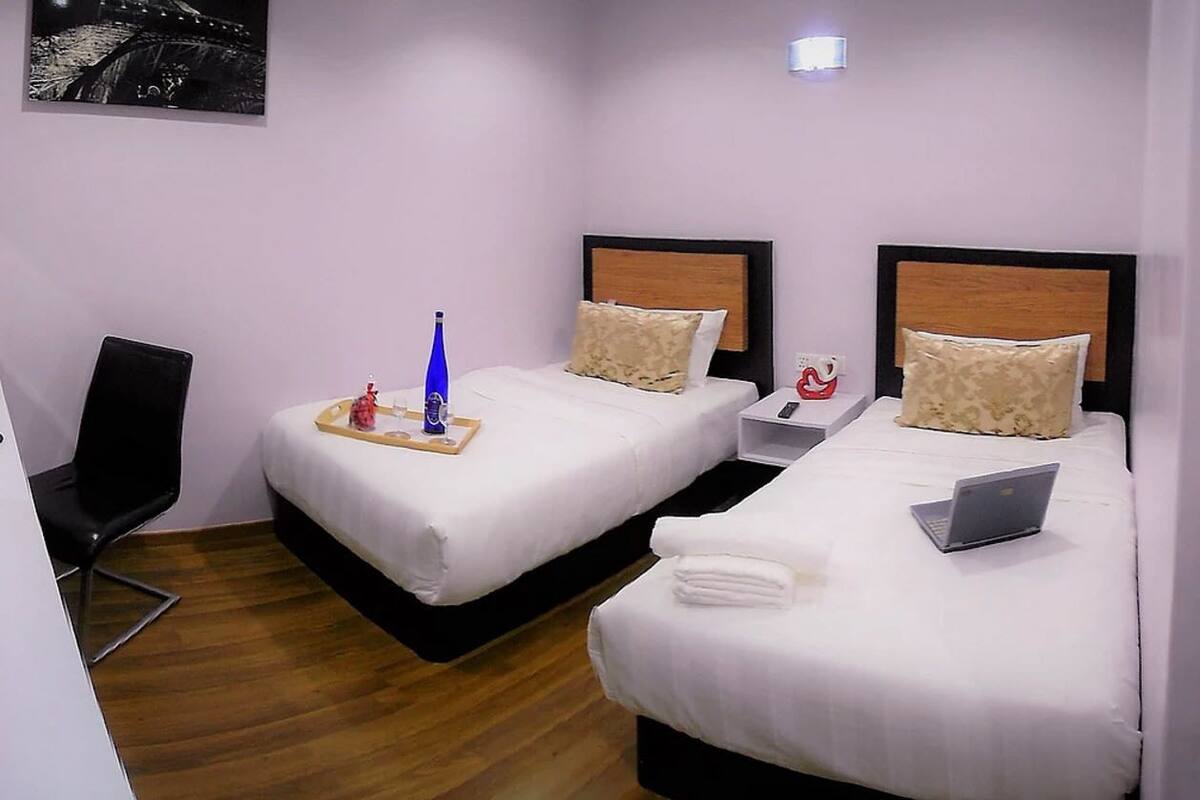A hotel room with two beds, a desk, and a chair.