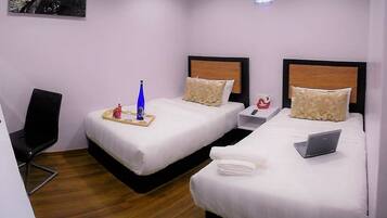 Quarto de hotel com duas camas, uma escrivaninha e uma cadeira.