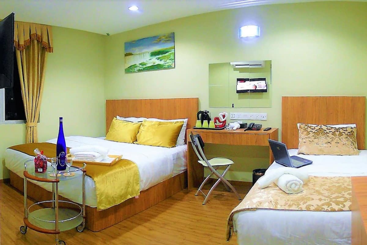 A hotel room with two beds, a desk, a chair, a cart with toiletries, and a painting on the wall.