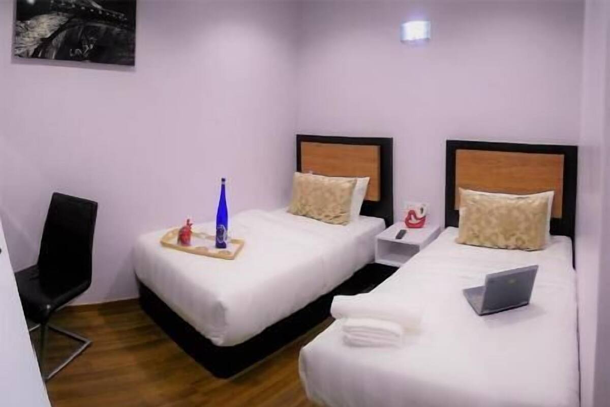 A hotel room with two beds, a desk, and a chair.