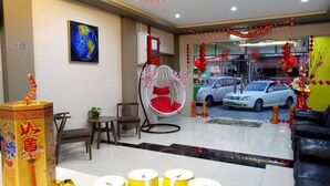 A hotel lobby with a traditional Chinese decorative centerpiece, a hanging chair, and a view of the street outside. - Royale Hotel (Batu Gajah)
