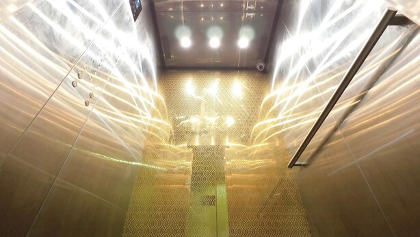 A modern elevator with a patterned floor and a metallic handrail. - Royale Hotel (Batu Gajah)