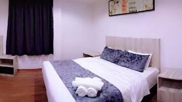 A hotel room with a bed, a nightstand, a small table, and a wall-mounted artwork.