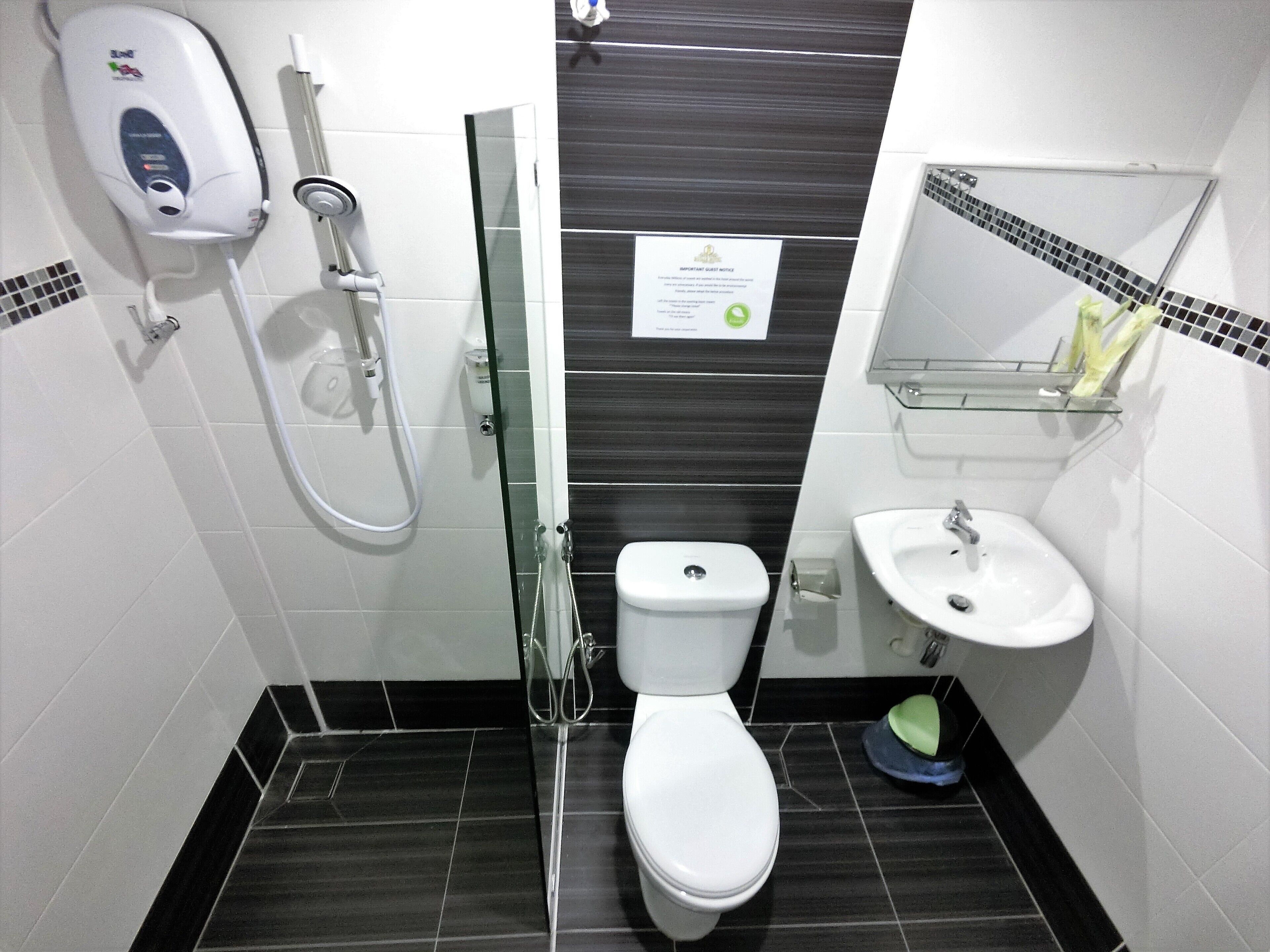 A compact bathroom with a toilet, a glass shower enclosure, a sink, and a soap dispenser.