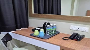 Un escritorio de hotel con un teléfono, una cafetera y botellas de agua.