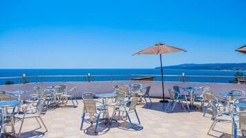 Una terraza con mesas al aire libre y vista al mar.