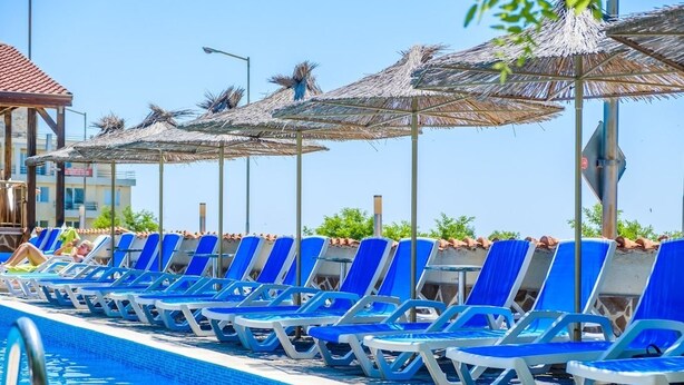 A poolside area with blue lounge chairs and thatched umbrellas. - Hotel Vemara Club (Byala)